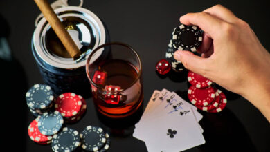 Casino chips, playing cards, glass of whiskey and dices on dark reflective background