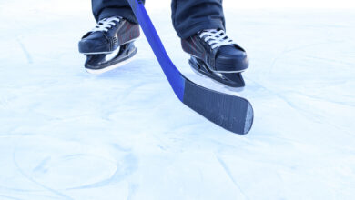 A man in skates on ice with a hockey stick. View only feet.