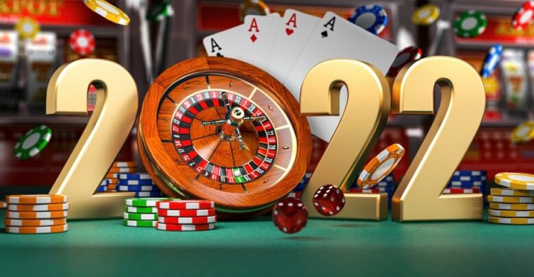2022 Happy New Year in casino. Numbers 2022 from roulette, casiino chips with dice and card on green table. 3d illustration